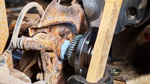 Mechanic replacing corroding wheel bearing on aged automobile component Stock Footage 332529680
