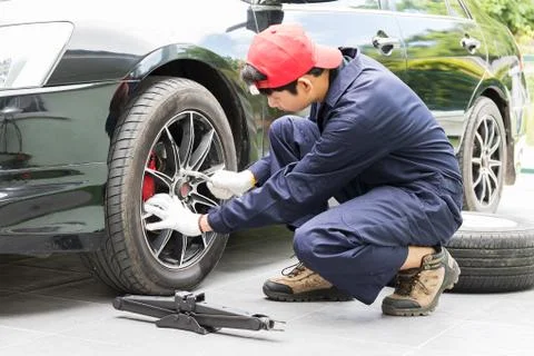 Mechanic replacing lug nuts changing tires on vehicle Stock Photos