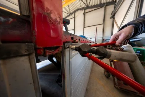 Mechanic Rivets Silver Side Panel on Red Bus in Industrial Workshop Stock Photos