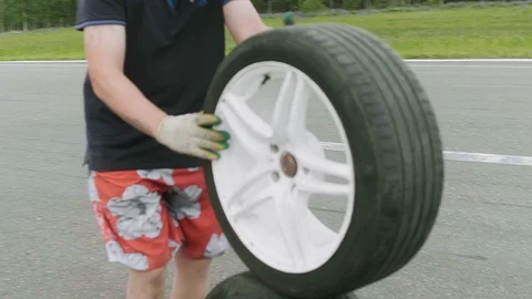 Mechanic rolls two newly assembled wheels one on top of another on a road Stock Footage 129510707