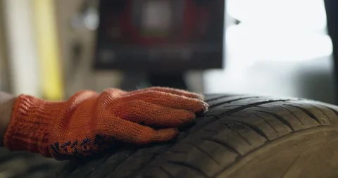 Mechanic rotates wheel and controls a balance process on monitor in auto service Video stock 127723381
