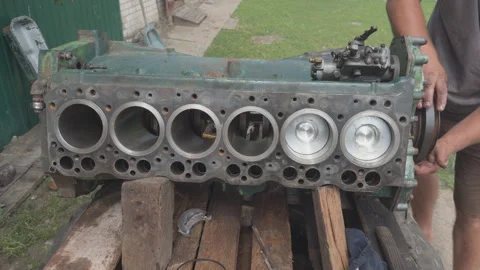 Mechanic rotating crankshaft on old six cylinder engine block Stock Footage 338410832