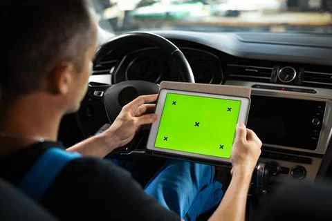 Mechanic running diagnostics software on tablet computer with green screen Foto stock
