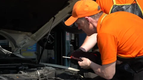 Mechanic senior man  checking oil level and wipes the oil dipstick of a car i Stock Footage 147367164
