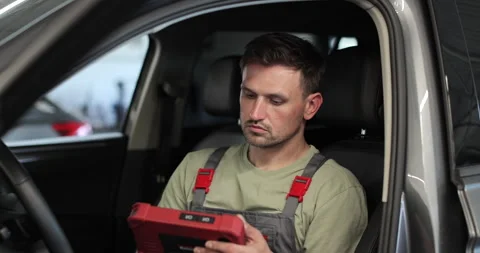 Mechanic sitting in car doing diagnostics on digital tablet. Stock Footage 341870489