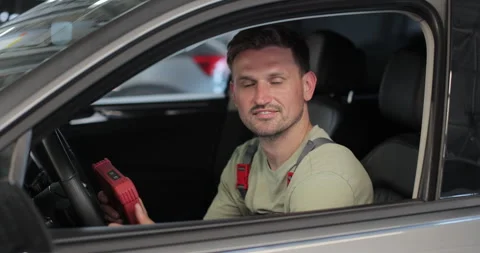 Mechanic sitting in car doing diagnostics on digital tablet. Stock Footage 341870598