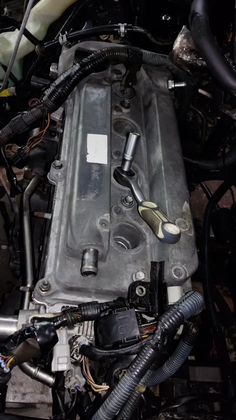 Mechanic socket wrench lying on a silver car engine valve cover Stock Footage 340415319