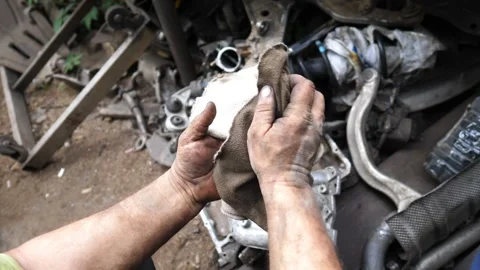 Mechanic with soiled hands is meticulously cleaning a cloth Stock Footage 324501112