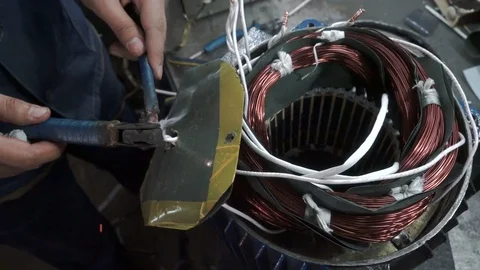 The mechanic solder two wires of the electrical winding. Electric motor Stock Footage 75341172