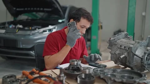 Mechanic speaks on phone while working on car parts Stock Footage 339546121