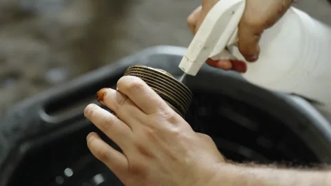 Mechanic spraying cleaner fluid on dirty oil filter cap tool Stock Footage 337569737