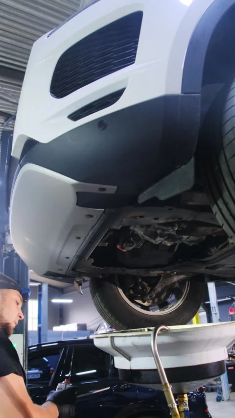 Mechanic sprays substance from can on underside of car Stock Footage 317652914