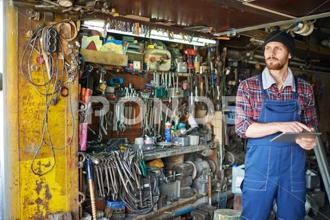 Mechanic standing in his repair shop with digital tablet Stock Photos