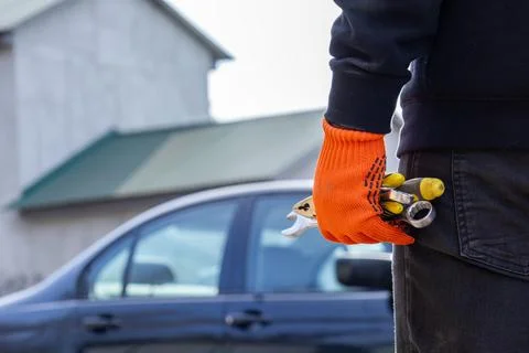 A mechanic stands confidently, gripping keys and tools, preparing to repair.. Stockfoto's
