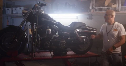 Mechanic starting up the motorcycle while checking it in shop Stock Footage 116361757