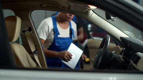 Mechanic with a tablet gets into a car and tells to colleague to take notes Stock Footage 124264018