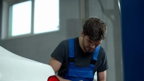 Mechanic with a tablet inspects the headlights of a car Stock Footage 124255331