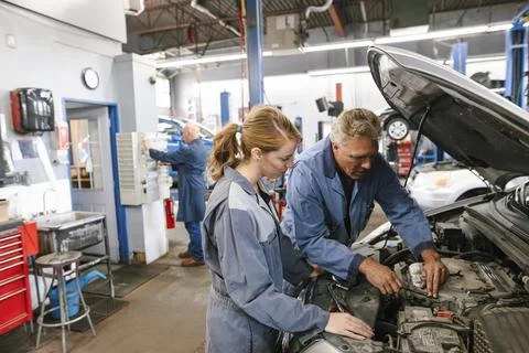 Mechanic teaching apprentice in automobile workshop Foto stock
