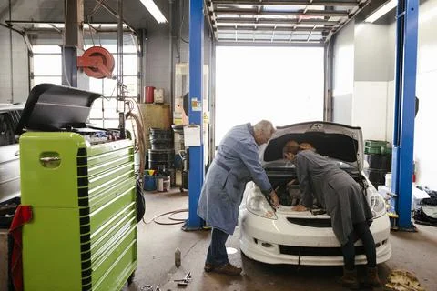Mechanic teaching apprentice in automobile workshop 스톡 사진