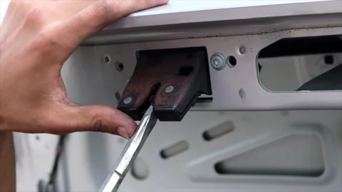 Mechanic testing automobile trunk latch locking mechanism with screwdriver .. Stock Footage 339373228