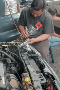 Mechanic testing headlight bulb with electric screwdrivers in a car  at the r Stock Photos
