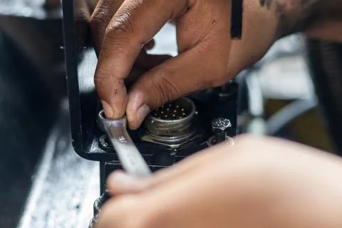 Mechanic tightens connector plug bolt on machinery using combination spanne.. Foto stock