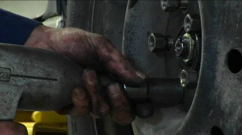 A mechanic tightens lug-nuts with a power tool in this close-up Stock Footage