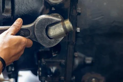 Mechanic tightens threaded elbow pipe fitting with heavy wrench on transmis.. Stock Photos
