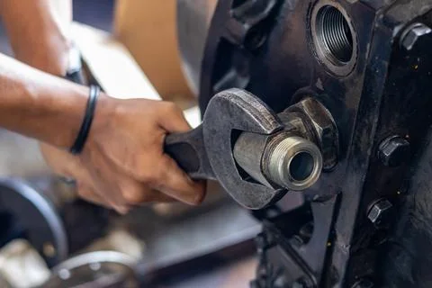 Mechanic tightens threaded elbow pipe fitting with heavy wrench on transmis.. Stock Photos