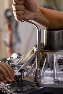 A mechanic turns a socket handle wrench to fasten gearbox housing bolts ind.. Foto stock
