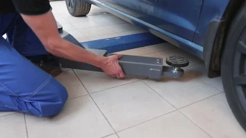 Mechanic in uniform installs a car on an elevator for inspection and repair Stock Footage 165836534