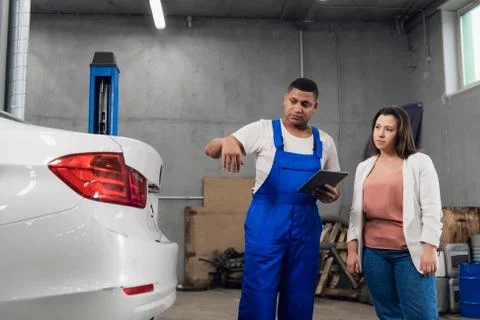 Mechanic in uniform talking to a client about a car Stock Photos