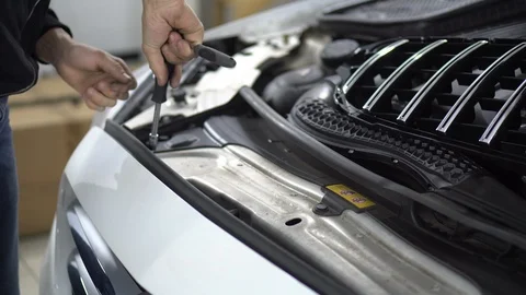 Mechanic unscrews the bolt securing the bumper of a car 動画素材 97837892