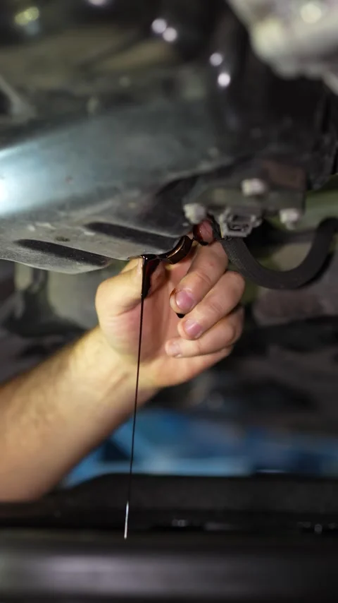 Mechanic unscrews the drain plug to change car engine oil. Stock Footage 345707827