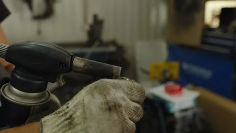 A mechanic uses a cigarette lighter to ignite a gas blowtorch Stock Footage 340153921