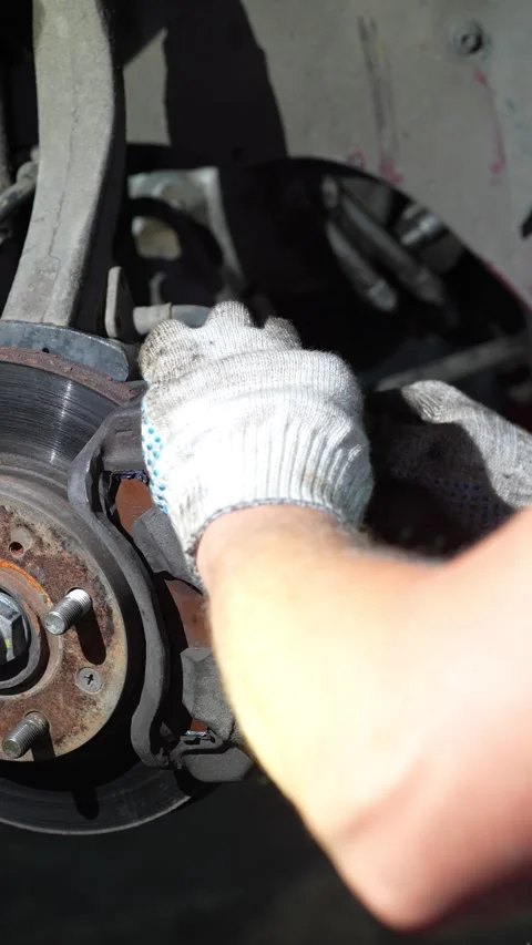 Mechanic uses a screwdriver to service a car brake caliper. Stock Footage 345708287