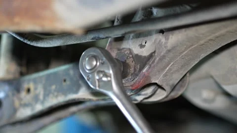 Mechanic uses a socket ratchet wrench to unscrew car suspension bolt. Stock Footage 345708096