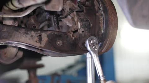 Mechanic uses a socket ratchet wrench to repair car rear suspension. Stock Footage 345708167