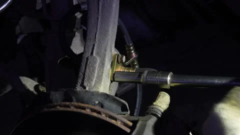 Mechanic uses a socket wrench to bolt brake hose bracket. Stock Footage 345709630