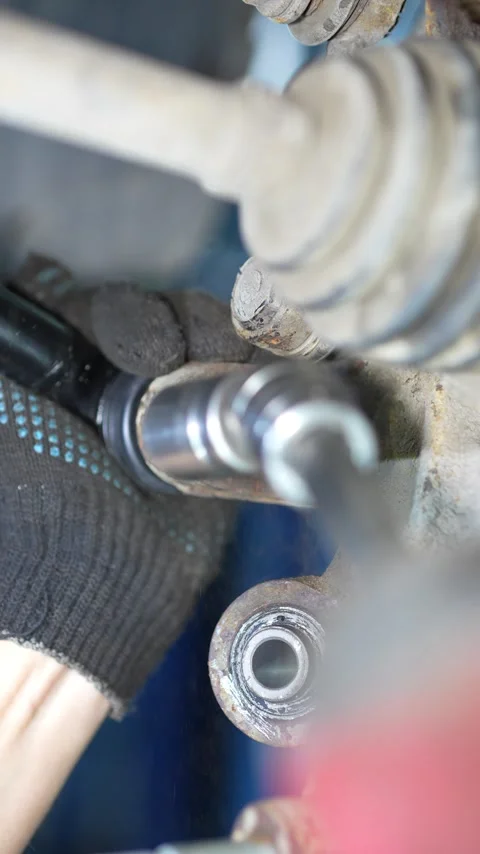 Mechanic uses a socket wrench to install suspension arm bolt. Stock Footage 345909590