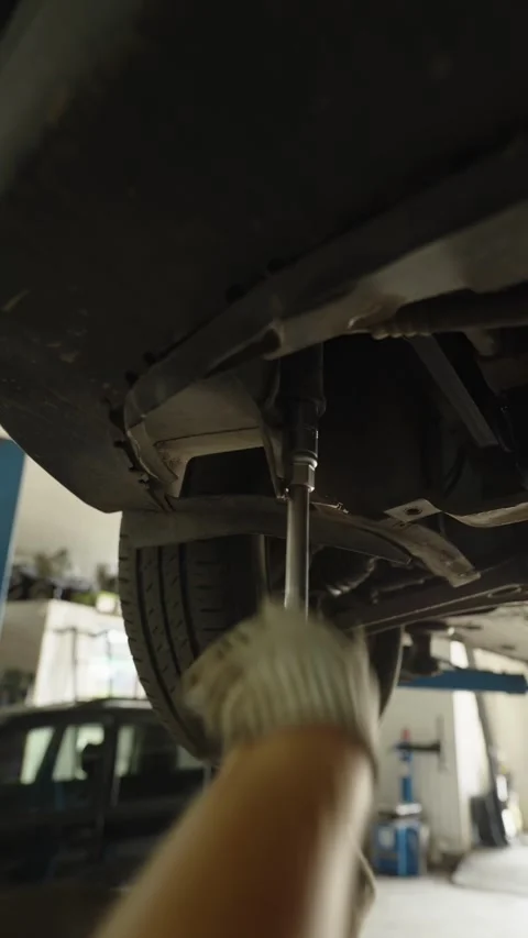 Mechanic uses a socket wrench to repair a car undercarriage Video stock 340154106