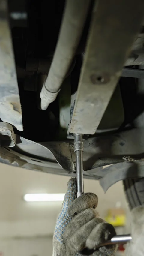 Mechanic uses a socket wrench to repair a car undercarriage Stock Footage 340154254