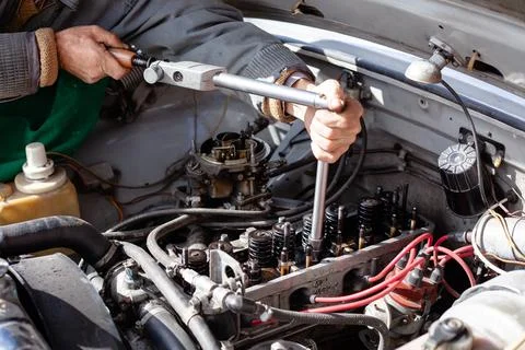 The mechanic uses a torque dynamometer wrench to install the cylinder head at Stock Photos