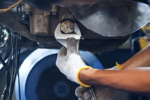 Mechanic Using Adjustable Wrench on Machinery Transmission Drain Plug. Stock Photos