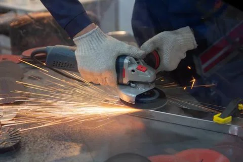 Mechanic using angle grinder and working with metal in workshop Stock Photos