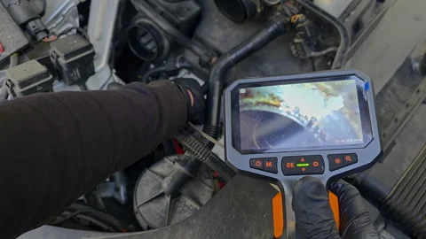 Mechanic using borescope camera to inspect engine internals, live view displayed Stock Footage 308495532