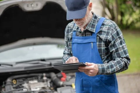 Mechanic using digital tablet for checking car engine Stock Photos