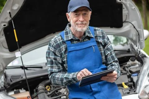 Mechanic using digital tablet for checking car engine Stock Photos
