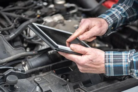 Mechanic using digital tablet for checking car engine Foto stock