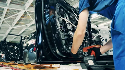 Mechanic is using an electric screwdriver to assemble a car door Vídeo Stock 142787642